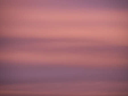Horizontal picture of a defocused clouds in the magenta colored sky during sunset