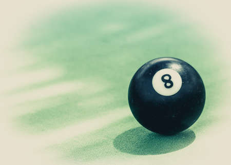 Black billard ball number eight on green billard table