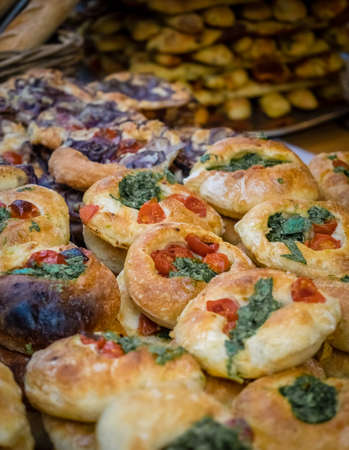 Close up of freshly baked spinach and tomato buns on market stall in Borough market in Londonの写真素材