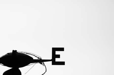 Monochrome image of an old weathervane pointing Eastの写真素材