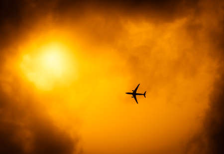 Commercial passenger plane flying over the dramatic golden evening skyの写真素材