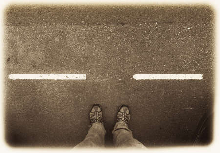 Man standing at a pedestrian crossing looking at his feet from aboveの写真素材