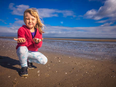 Young caucasian girl presenting small mussels found on the beachの写真素材
