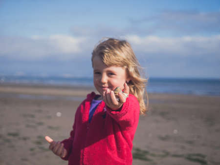Young caucasian girl presenting small mussels found on the beachの写真素材