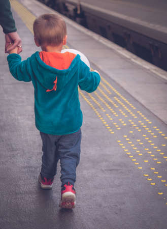 Little boy walking with his mother on the platform on the train station in Edinburgh, Scotlandの写真素材
