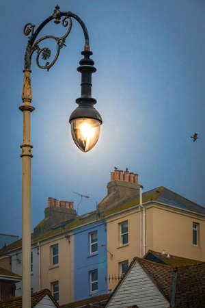 Lit lamppost and the colorful houses on a hillside in the old town of Hastings, East Sussex, England, UKの写真素材