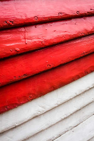 Red and white rows of painted wooden side of a fishermen boatの写真素材