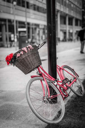 Red and pink bicycle with a basket attached on the street in London centreの写真素材
