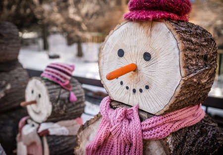 Close up of a nose of a snowman made of wooden log wearing purple and pink hat and scarfの写真素材