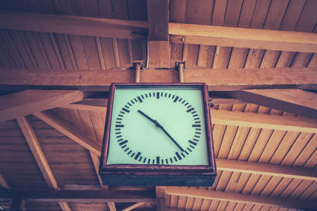 Old retro clock at the train station with a wooden roofの写真素材