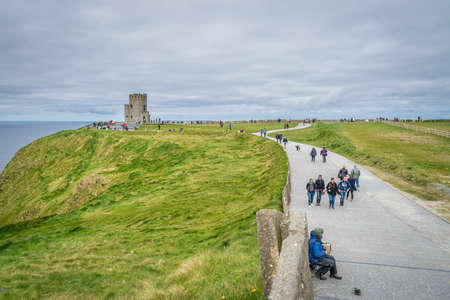 Cliffs of Moher, Ireland -  April 2017 : Tourists walking on a pathway leading to the O Briens Tower at the Cliffs of Moher, Irelandのeditorial素材