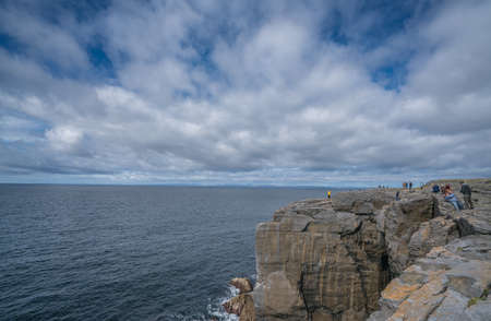 Cliffs of Moher, Ireland -  April 2017 : Group of tourists standing on the cliffs edge in Doolins Bay, The Burren, County Clare, Irelandのeditorial素材