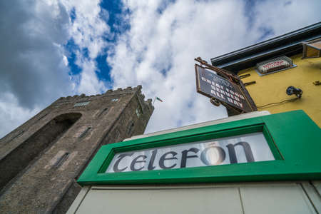 Bunratty castle, Ireland -  April 2017 : Old retro vintage telephone booth in front of a traditional pub with the Bunratty castle in the background, county Clare, Irelandのeditorial素材