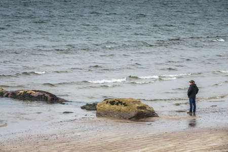 Waterville, Ireland -  April 2017 : Man standing on the seashore in Ballingskelligs Bay Beach, Waterville, County Kerry, Irelandのeditorial素材