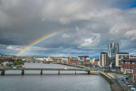 Limerick, Ireland -  April 2017 : Half of a rainbow over river Shannon, hotels and commercial buildings in Limerick town, Irelandのeditorial素材