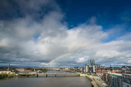 Limerick, Ireland -  April 2017 : Half of a rainbow over river Shannon, hotels and commercial buildings in Limerick town, Irelandのeditorial素材