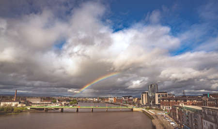 Limerick, Ireland -  April 2017 : Half of a rainbow over river Shannon, hotels and commercial buildings in Limerick town, Irelandのeditorial素材