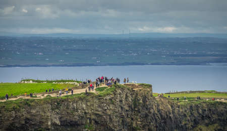 Cliffs of Moher, Ireland -  April 2017 : People walking on a path on top of the Cliffs of Moher on a overcast, cloudy and gloomy day, Irelandのeditorial素材