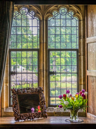 Hever Castle, England -  April 2017 : Small engraved mirror and colorful tulips in a vase on a windowsill in an old buildingのeditorial素材