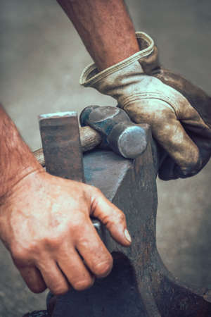 A blacksmith resting his hands on anvil after work at medieval fair festival in Streatham Park in Londonの写真素材