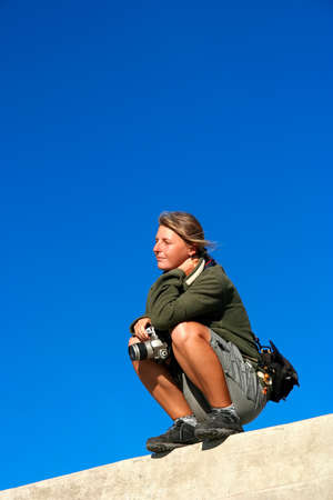 Woman with her DSLR camera on top of a wall waiting for a good photo opportunityの写真素材