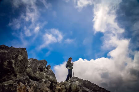 Lonely female trekker admiring mountain view from the topの写真素材