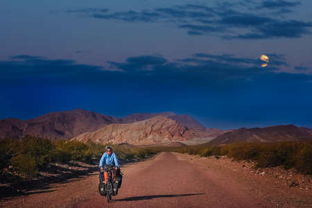 Woman cycling at night on the empty road in the remote part of Argentinaの写真素材