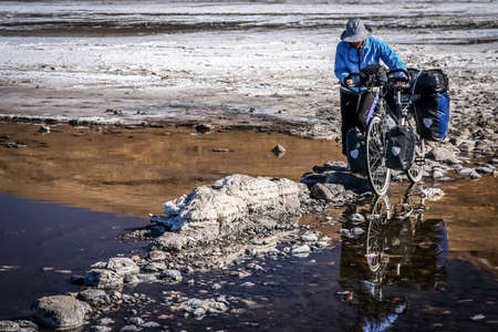 Lonely female cyclist travelling through the biggest salar in the world, Salar de Uyuni in Boliviaの写真素材