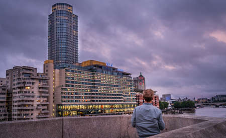 London, England - July 26, 2017 :  Man standing on the Blackfrairs bridge at dusk looking at the Oxo and South Bank Towers buildings, Londonのeditorial素材