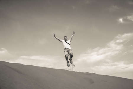 Tourist jumping in the air at the stunning sand dunes of Sahara desert, Merzouga, Morocco