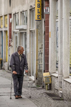 Bydgoszcz, Poland -  August 2017 : Old disabled man walking with crutches on the street in townのeditorial素材