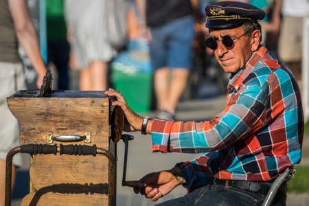 Sarbinowo, Poland -  August 2017 : Street busker with a sunglasses and hat playing on an old wooden organette instrumentのeditorial素材