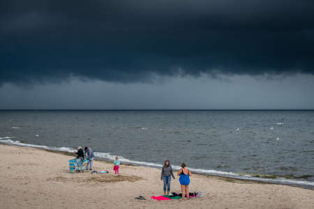Sarbinowo, Poland -  August 2017 : Tourists leaving the Baltic sea beach due to the incoming storm and rainのeditorial素材