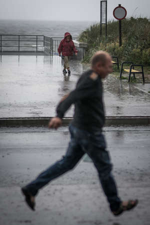 Sarbinowo, Poland -  August 2017 : Bedraggled man walking on a pavement during a downpourのeditorial素材