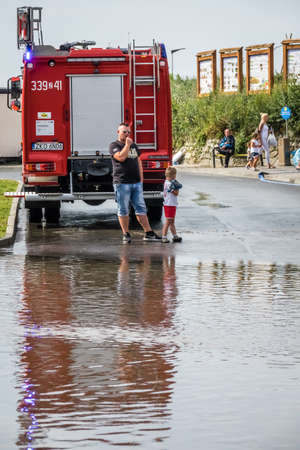 Sarbinowo, Poland -  August 2017 : Father and son watching firefighters pumping out excess water...