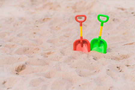 Two red, yellow and green childrens beach toys on a beautiful white sand seashoreの写真素材