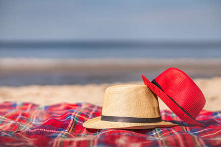 Red and white straw hats on the colorful blanket on the 
 beach in summerの写真素材