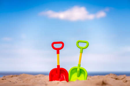 Two red, yellow and green childrens beach toys on a beautiful white sand seashoreの写真素材