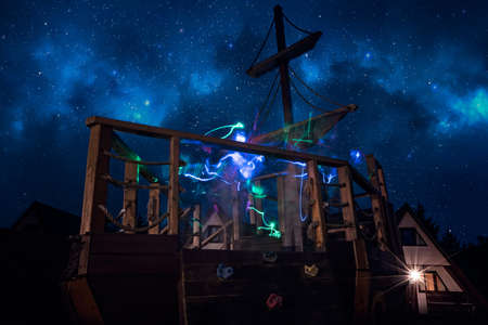 Colorful ghostly lighttrails on a deck of a wooden pirate ship on a children playground at nightの写真素材