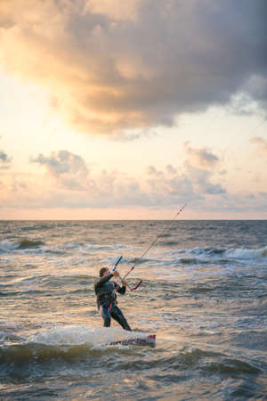 Sarbinowo, Poland -  August 2017 :  Extreme sport performer parachute surfing in the rough sea at duskのeditorial素材