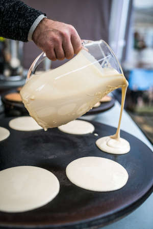 Men preparing delicious pancakes on the street food market in Bergen, Norwayの写真素材