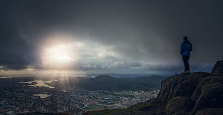 Unidentifiable tourist standing on the top of mount Ulriken in Bergen and looking at the landscape below, Norwayの写真素材