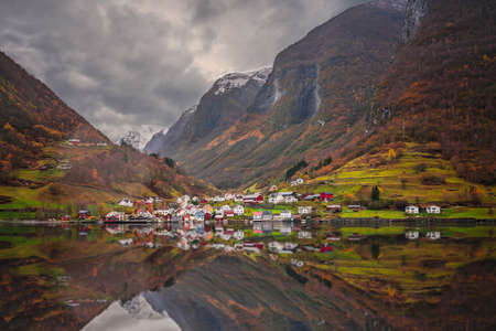Small homes on the shore of a fjord photographed from a Fjords sightseeing cruise boat leaving Flam in autumn, Norwayの写真素材