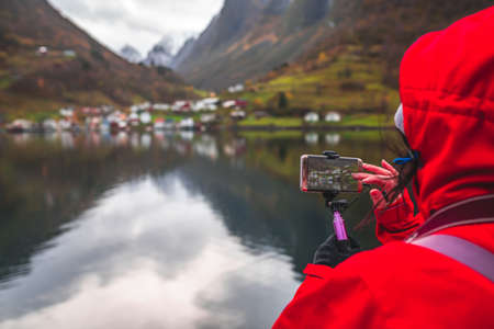 Tourist taking pictures on a smartphone of beautiful fjords during Norway in a nutshell sightseeing cruise through the magnificent Aurlandsfjord and the narrow NÃ¦rÃ¸yfjordの写真素材