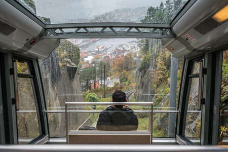 Bergen, Norway -  October 2017 :  Lonely male passenger sitting inside the cabin in the Floibanen funicular heading downhill from Mount Floyen, Bergen, Norwayのeditorial素材