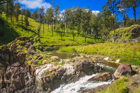 River ending in a waterfall with a water coming out of crater lake of Gunung Rinjani volcano, Lombok island, Indonesiaの写真素材