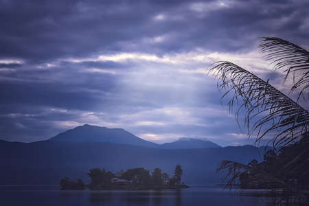 Small home on the tiny island in the middle of the stunning Lake Maninjao at sunset, Sumatra Island, Indonesiaの写真素材