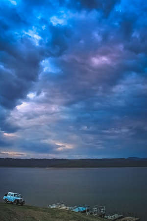 Four wheel drive car parked on the shore of an argentinian lake during dramatic sunset, Salta region...