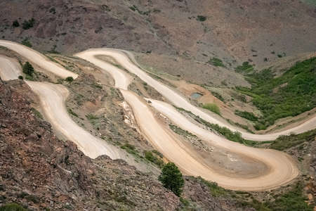 Twisting serpentine gravel downhill road from Mirador Bajada del Rahue in the mountains in Argentina, South Americaの写真素材