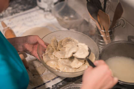 Female putting pierogi, taditonal Polish food, in a glass bowl, ready to be servedの写真素材
